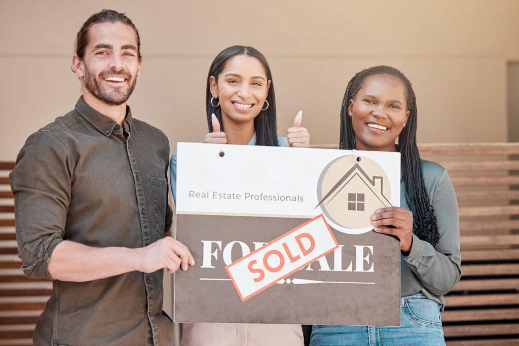 Residential property conveyancing – happy buyers holding a sold sign